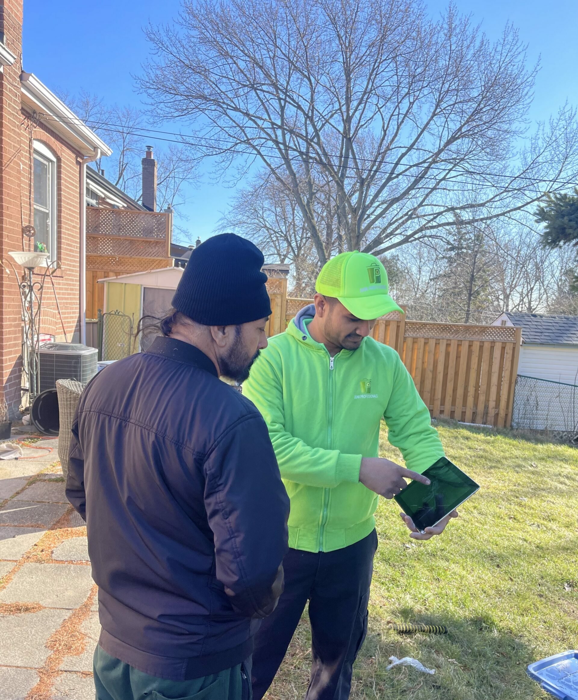 Junk professionals team member showing pricing on a tablet to customer for junk removal service